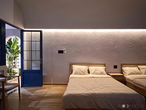 波来古市MOONLIGHT Homestay & Hotel的一间卧室设有两张床和一扇蓝色的门