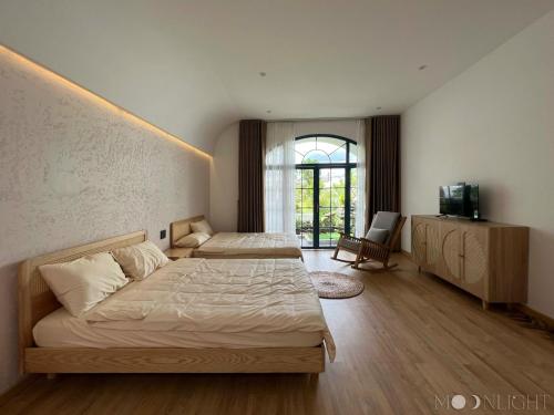 波来古市MOONLIGHT Homestay & Hotel的一间卧室配有两张床和电视。