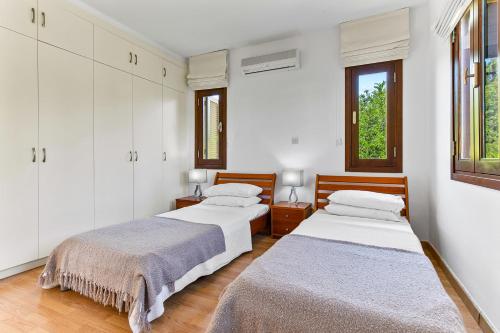 库克里亚2 bedroom Apartment Anatoli with communal pool, Aphrodite Hills Resort的配有2张床的白色墙壁和窗户客房