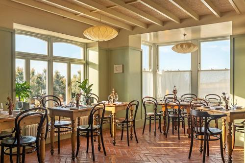 马盖特Fort Road Hotel的用餐室设有桌椅和窗户。