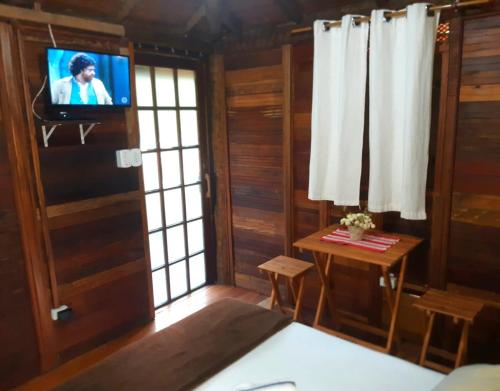 特林达德Pousada Recanto Afetivo的客厅配有电视和带桌子的桌子。