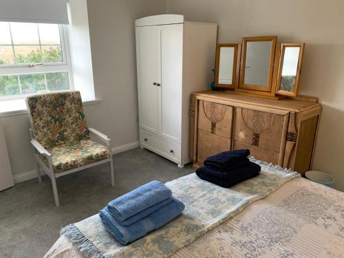 斯托诺韦Sighthill Cottage, North Tolsta的一间卧室配有一张床、一把椅子和镜子