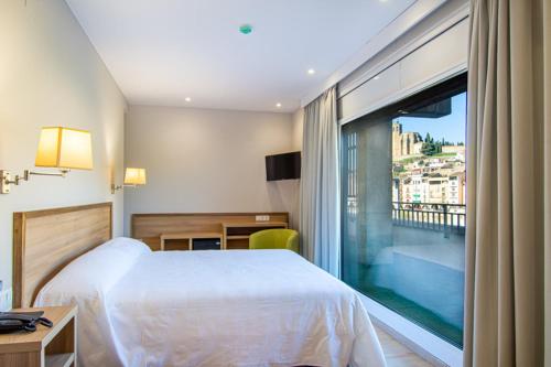 巴拉格尔HOTEL JAUME D'URGELL的酒店客房设有一张床和一个大窗户