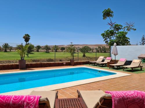 卡勒达德福斯特Beautiful Villa Grace, Caleta de Fuste的游泳池周围设有躺椅和椅子