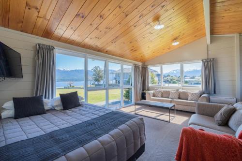 蒂阿瑙Te Anau Motel & Apartments的一间卧室配有一张床、一张沙发和窗户。