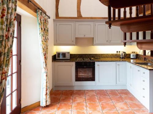 Milnathort夫奇小屋的厨房配有白色橱柜和瓷砖地板。