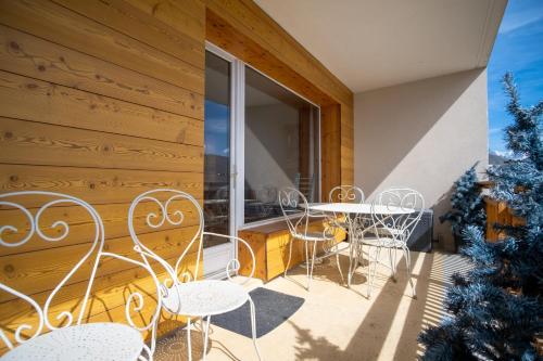 于埃Superb apartment with balcony in the heart of Huez - Welkeys的阳台配有白色的桌椅和窗户。