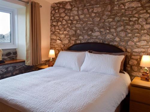 RowlstoneAugustus Cottage的一间卧室设有一张带石墙的大床