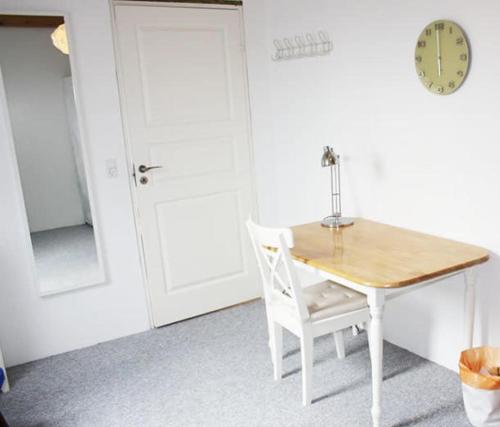SkovlundeDejligt værelse lyst og hyggeligt的一张桌子和椅子,放在一个钟表的房间