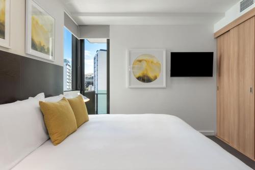 布里斯班Quattro Apartments的卧室配有一张带黄色枕头的大型白色床。