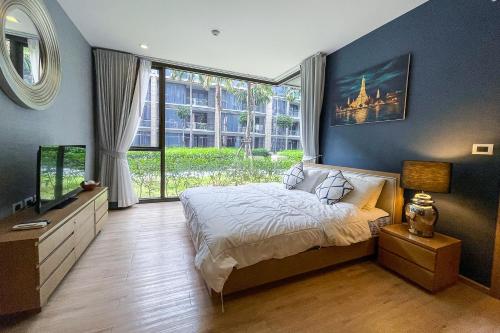 迈考海滩Baan Mai Khao - 2 Bedroom Luxury Condo- Direct Pool & Beach Access的一间卧室设有一张床和一个大窗户