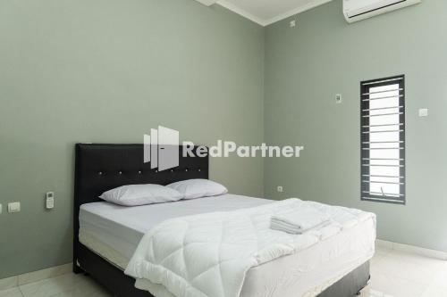 SukoharjoAthena House Syariah Near The Park Mall Solo Baru Mitra RedDoorz的一间卧室配有带白色床单和白色枕头的床。