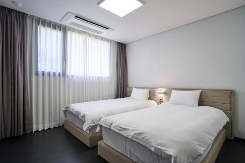 西归浦市Jeju Hana Resort的酒店客房设有两张床和窗户。