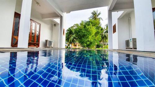恰洛克拉姆Baan Bhuwann Holiday Apartment的房屋中间的游泳池