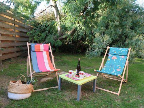 康卡勒Chalet Le Chalet - A的两把草坪椅和一张桌子,上面放着一瓶葡萄酒