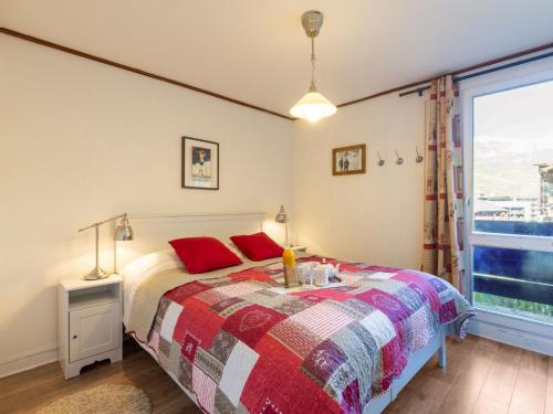 蒂涅Apartment Le Pramecou-11 by Interhome的一间卧室配有一张带红色枕头的床和一扇窗户