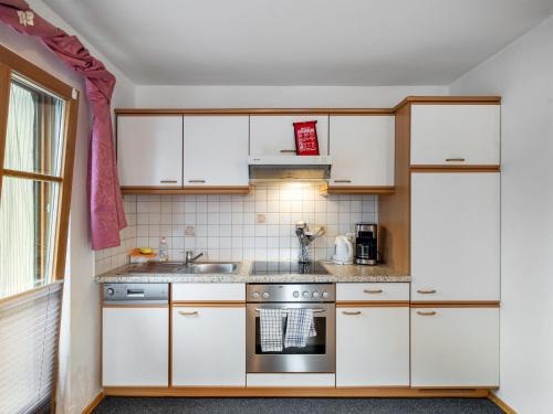 萨菲登安斯泰内嫩米尔Apartment Kitzsteinhorn by Interhome的厨房配有白色橱柜和炉灶。