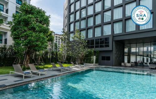 芭堤雅市中心Best Western Plus Nexen Pattaya的大楼前的游泳池