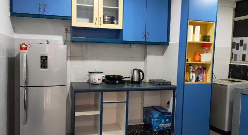 吉隆坡Cozzzzy Two Next to Axiata Arena, Bukit Jalil的厨房配有蓝色橱柜和带冰箱的台面
