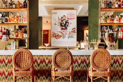 里斯本Hotel das Amoreiras - Small Luxury Hotels of the World的酒吧里摆放着三把藤椅和一张海报