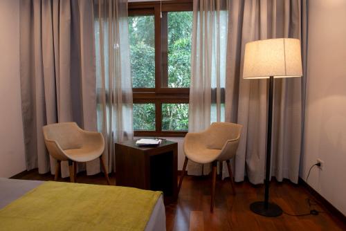 伊瓜苏港Hotel Tré Iguazú的一间卧室配有两把椅子、一盏灯和一扇窗户