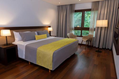 伊瓜苏港Hotel Tré Iguazú的一间卧室配有一张带黄色毯子的大床