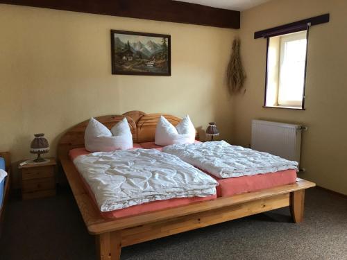 Ferienwohnung 1 vom Friesenhof Wieratal的卧室配有一张带白色床单和枕头的大床。