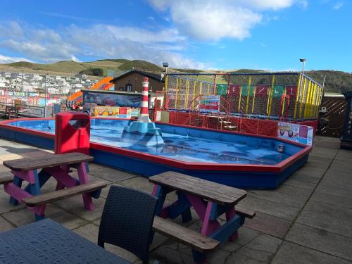 阿伯里斯特威斯Beautiful 2-Bed Chalet in Aberystwyth的大型游泳池设有2张桌子和2个长凳