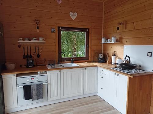 Pewel WielkaChata z Kraja的厨房配有白色橱柜、水槽和窗户。