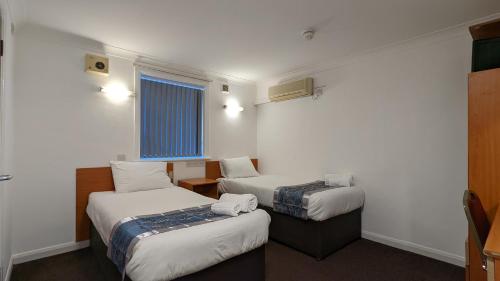 海斯SK Heathrow Hotel的酒店客房设有两张床和窗户。