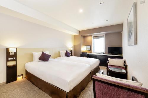 神户KOKO HOTEL Kobe Sannomiya的酒店客房设有一张大床和一张书桌。