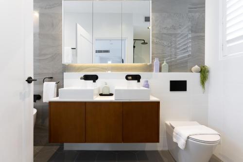 悉尼Barangaroo Park Apartments by Urban Rest的一间带水槽、卫生间和镜子的浴室