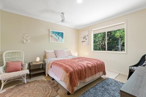 拜伦湾Treetops Lakeside Apartments的一间卧室设有一张床、一个窗口和一把椅子
