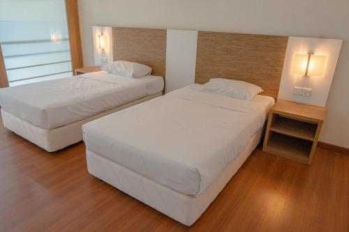 峇六拜The CEO Executive Suites的配有白色床单的酒店客房内的两张床
