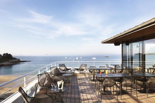 佩罗斯-吉雷克Grand Hôtel Perros-Guirec的阳台配有桌椅,俯瞰着大海