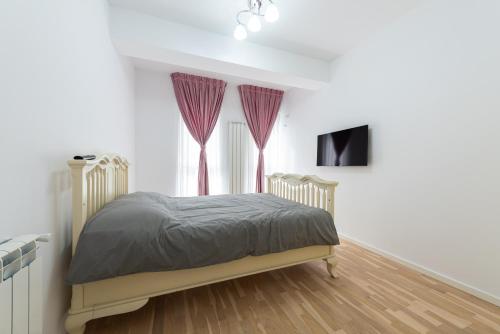 布加勒斯特Ines的一间卧室配有一张带紫色窗帘的床和一台电视。