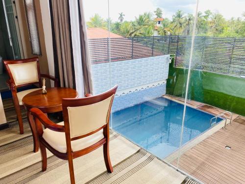 DivulapitiyaSundale Hotel的客房设有桌椅和窗户。