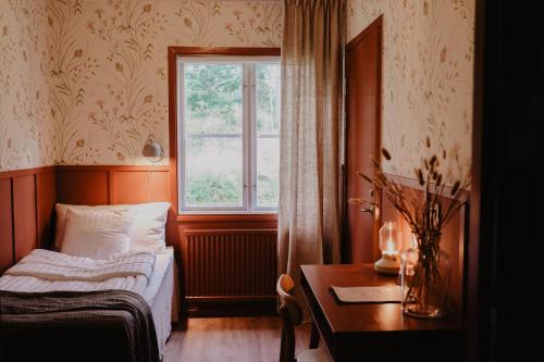 斯切灵加德Stiftsgården Tallnäs的一间卧室设有一张床、一个窗口和一张桌子