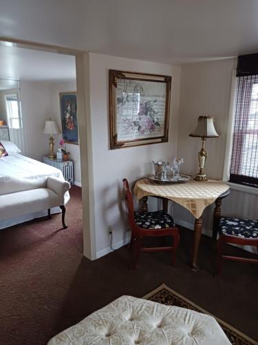MoosicThe guest house at the regina house tea room的酒店客房带一张床、一张桌子和椅子