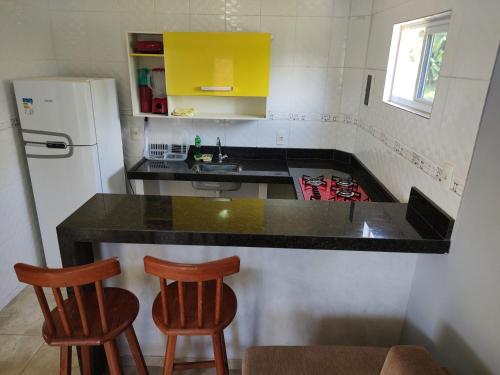 雅帕拉廷加Apart. japaratinga的厨房配有黑色柜台和2张木凳