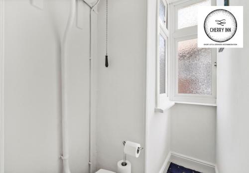 剑桥3 Bedroom House with Parking & Garden By Cherry Inn Short Lets & Serviced Accommodation Cambridge的白色的浴室设有卫生间和窗户。