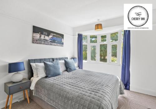剑桥3 Bedroom House with Parking & Garden By Cherry Inn Short Lets & Serviced Accommodation Cambridge的一间卧室配有一张带蓝色窗帘的床和一扇窗户