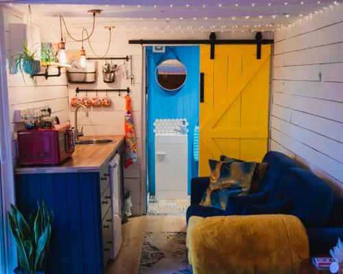 GaradiceThe Horrrsebox Tinyhouse Glamping的厨房设有蓝色的沙发和黄色的门