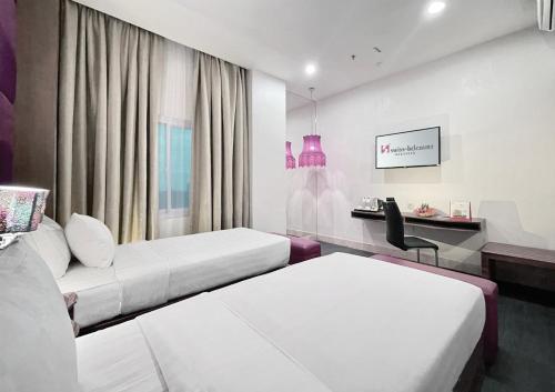 马卡萨Swiss-Belcourt Makassar的酒店客房配有两张床和一张书桌