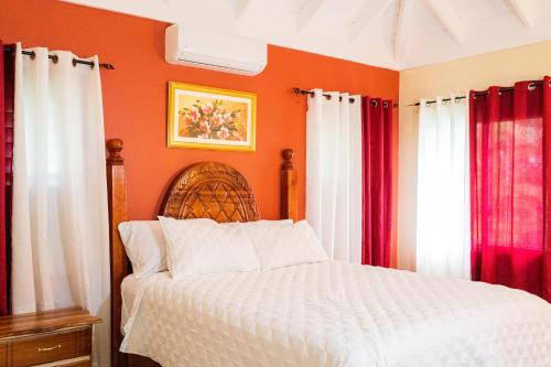 RichmondPALMS ESCAPE - 3 BEDROOM VACATION HOME的一间卧室配有橙色墙壁和红色窗帘的床