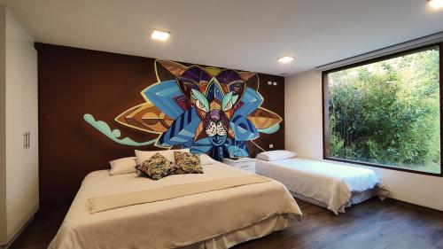 巴尼奥斯593 Hotel Boutique Baños的一间卧室设有两张床,墙上挂着一幅画