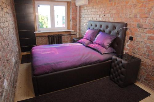 里加Mini cinema & movie studio with PS5的砖房的一张床位,配有紫色床单和枕头