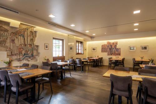 菲斯普Hotel-Restaurant Eyholz的餐厅设有桌椅,墙上挂有绘画作品