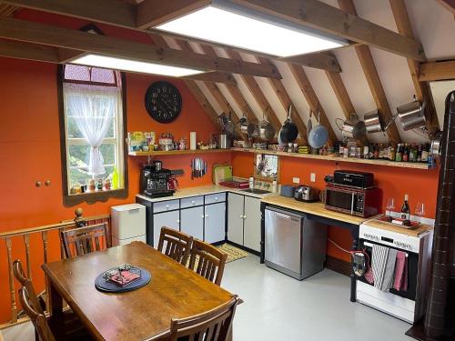 凯库拉Cubby House Stay Kaikoura的厨房设有橙色墙壁、木桌和用餐室。