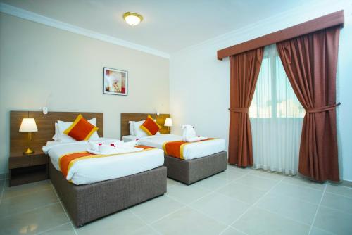 多哈La Villa Inn Hotel Apartments的酒店客房设有两张床和窗户。